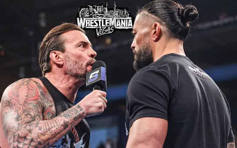 CM Punk talking on the microphone to Roman Reigns with a WrestleMania Vegas logo above